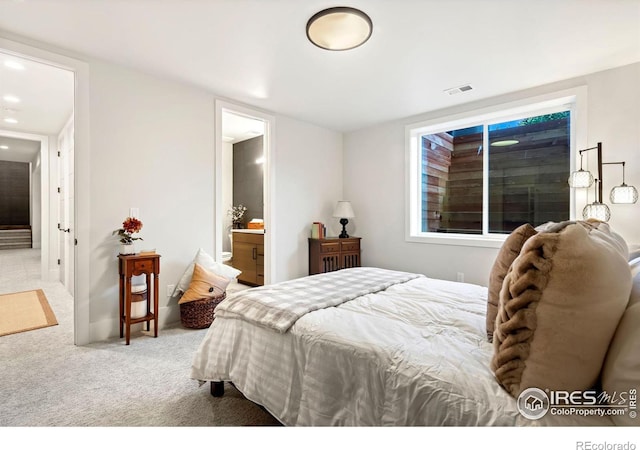 bedroom with ensuite bathroom and carpet flooring