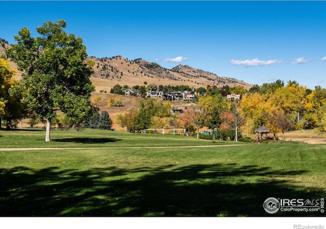 surrounding community with a mountain view and a lawn