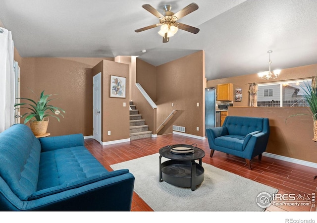 living room featuring vaulted ceiling and ceiling fan with notable chandelier