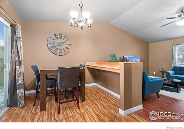 dining space with ceiling fan with notable chandelier and vaulted ceiling