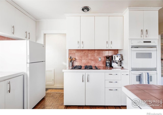 kitchen featuring white cabinets, white appliances, and parquet flooring