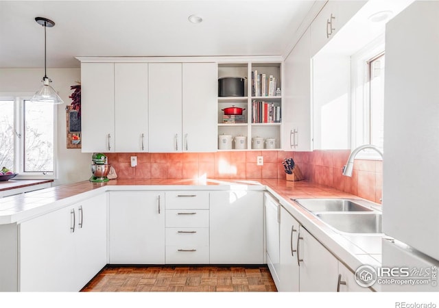 kitchen with a wealth of natural light, white cabinetry, pendant lighting, and sink