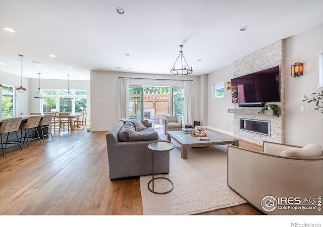 living room featuring a stone fireplace and light hardwood / wood-style flooring