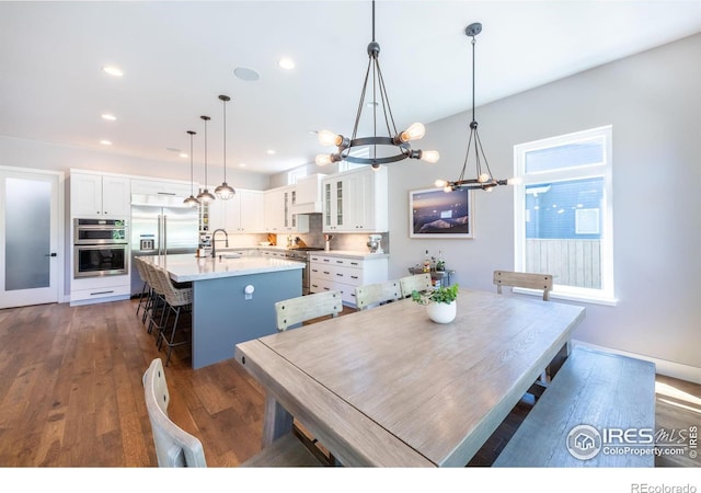 dining space with sink, dark hardwood / wood-style floors, and a notable chandelier