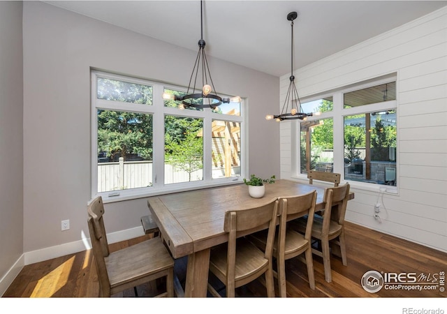 dining space with dark wood-type flooring and wooden walls