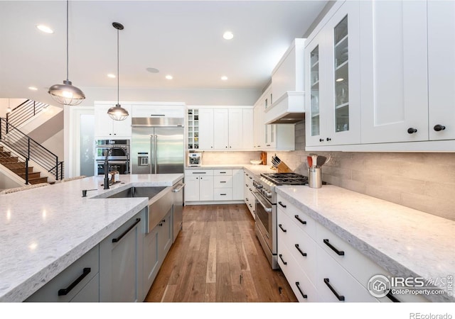 kitchen featuring decorative light fixtures, light stone countertops, white cabinetry, and high quality appliances