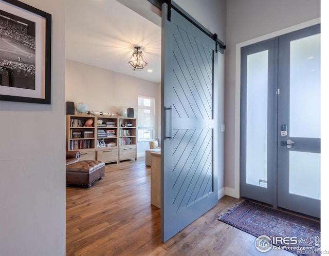 foyer entrance with a barn door, french doors, and wood-type flooring