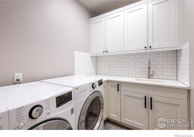 clothes washing area with cabinets, sink, and washing machine and dryer