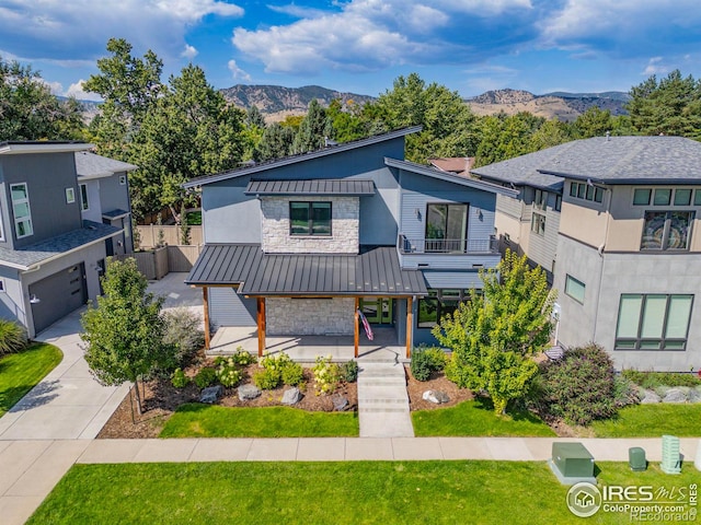 view of front of house with a garage, a mountain view, covered porch, and a front yard