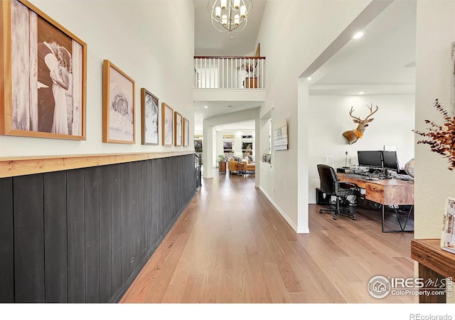 foyer featuring wood-type flooring, a chandelier, and a high ceiling