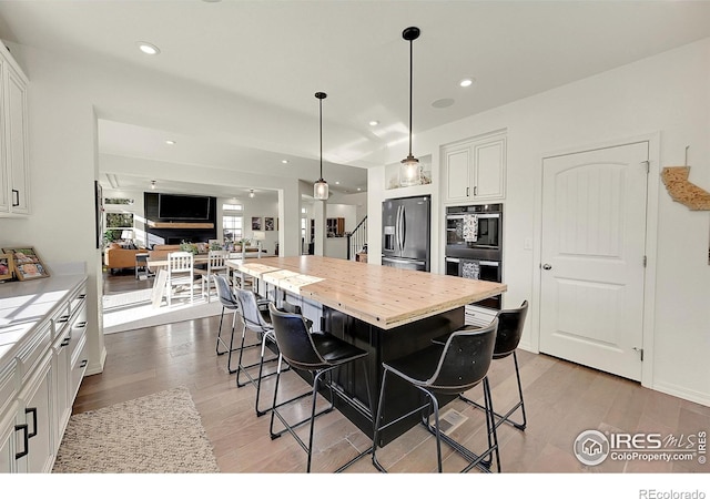 kitchen with white cabinets, a center island, stainless steel refrigerator with ice dispenser, and a kitchen breakfast bar