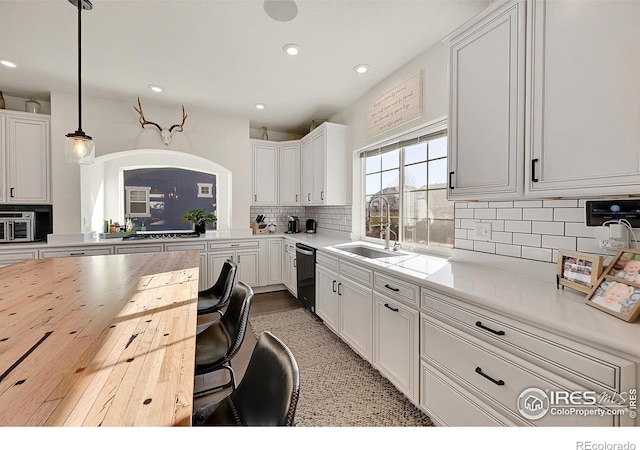 kitchen featuring dishwasher, hanging light fixtures, sink, white cabinetry, and tasteful backsplash