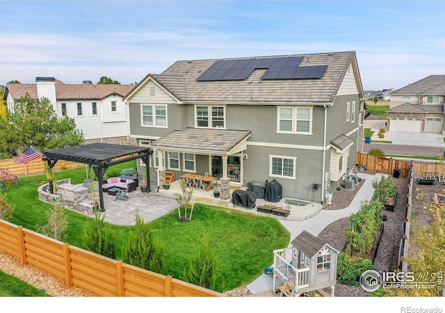 rear view of house featuring a pergola, an outdoor living space with a fire pit, a patio, solar panels, and a lawn