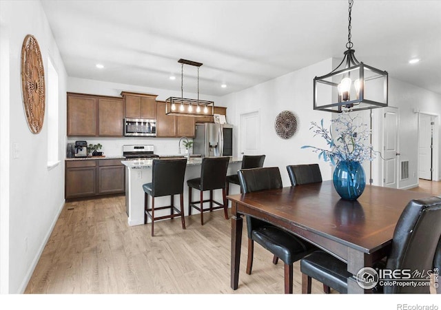 dining room featuring light wood-type flooring and an inviting chandelier