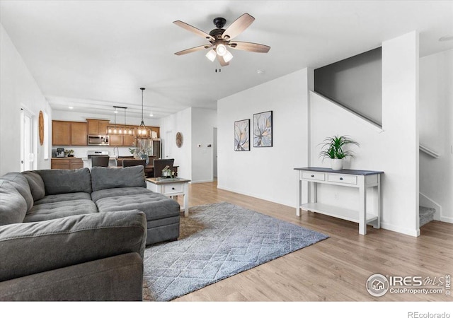 living room with ceiling fan with notable chandelier and hardwood / wood-style floors