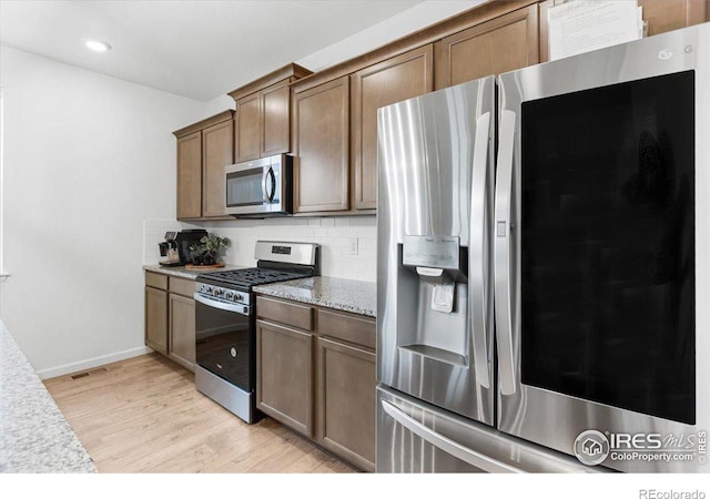 kitchen featuring light wood-type flooring, appliances with stainless steel finishes, and tasteful backsplash