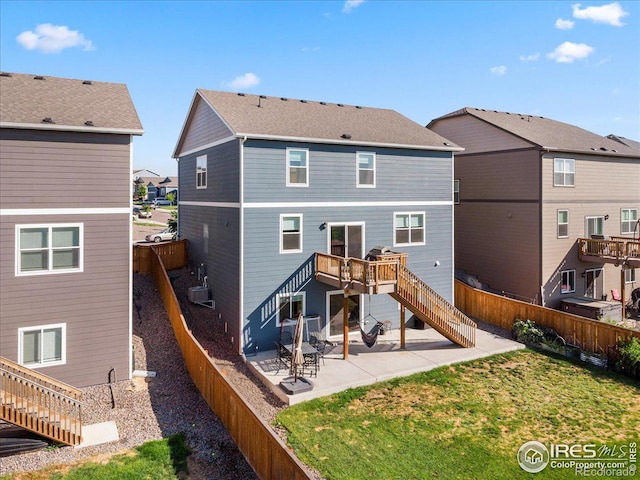 back of house with a wooden deck, a yard, and a patio