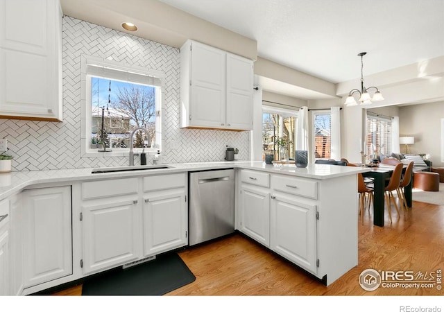 kitchen with sink, dishwasher, white cabinetry, decorative light fixtures, and kitchen peninsula