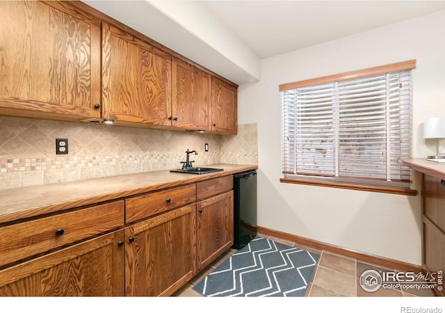 kitchen featuring dark tile patterned floors, dishwasher, sink, and decorative backsplash