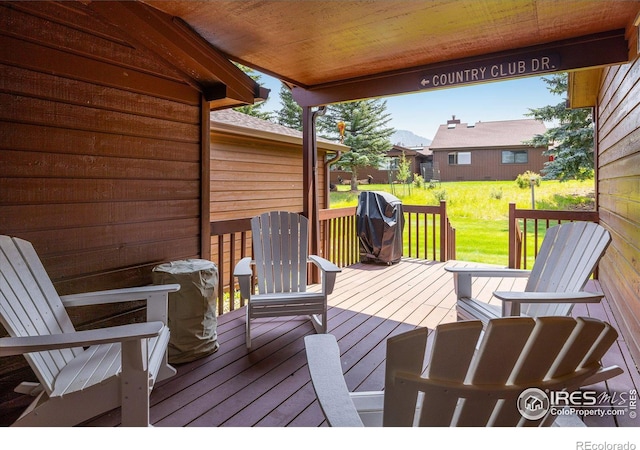 wooden terrace featuring grilling area and a yard