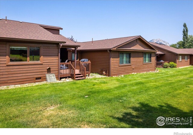 rear view of house featuring a yard and a deck