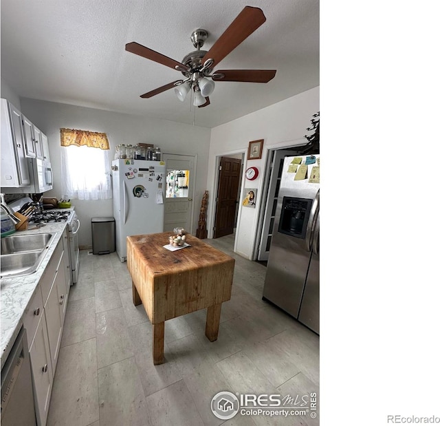 kitchen featuring sink, white cabinetry, a textured ceiling, ceiling fan, and white appliances