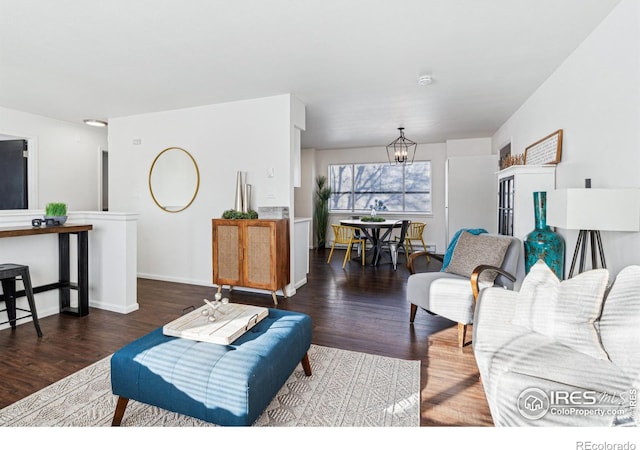 living area featuring baseboards, wood finished floors, and an inviting chandelier