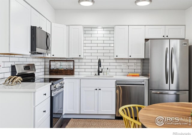 kitchen with stainless steel appliances, light countertops, a sink, and decorative backsplash