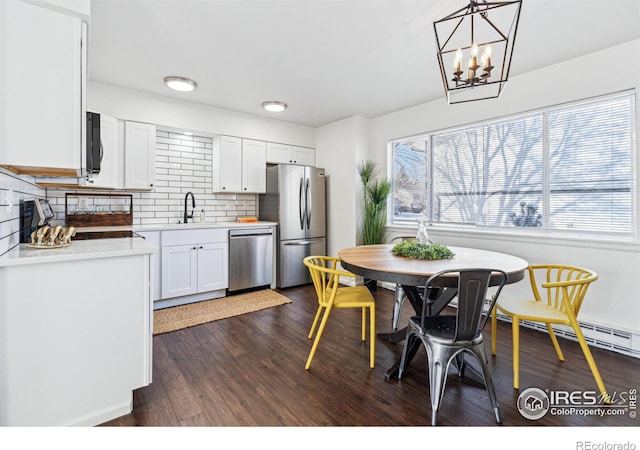 kitchen featuring decorative backsplash, appliances with stainless steel finishes, dark wood-type flooring, light countertops, and a sink