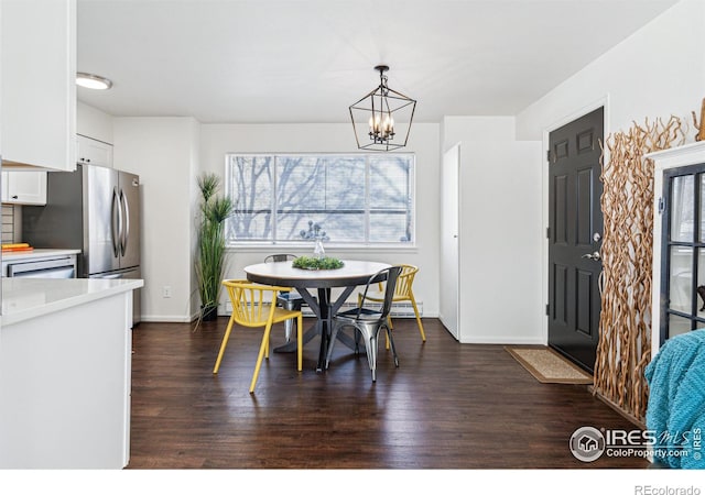 dining space with dark wood-style floors, a chandelier, and baseboards