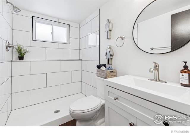 bathroom featuring vanity, a tile shower, and toilet