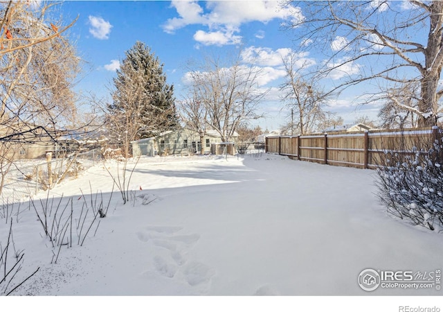 yard layered in snow featuring fence