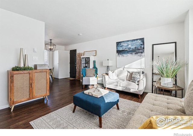 living room with an inviting chandelier, baseboards, and wood finished floors