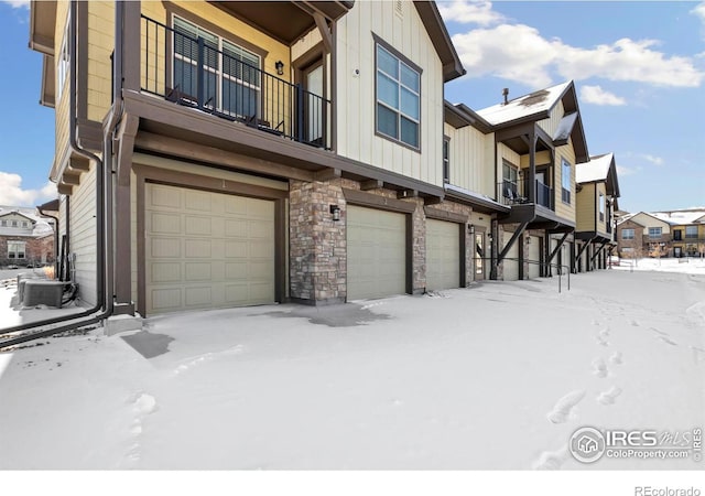 view of snowy exterior featuring a balcony and a garage