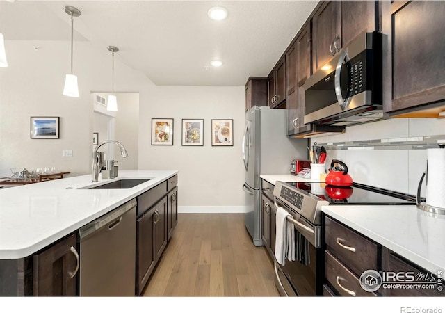 kitchen featuring light hardwood / wood-style floors, sink, dark brown cabinetry, decorative light fixtures, and stainless steel appliances