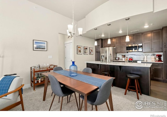 dining space with sink, light carpet, and a notable chandelier