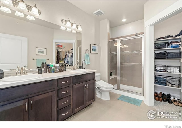 bathroom with vanity, toilet, a shower with door, and tile patterned flooring