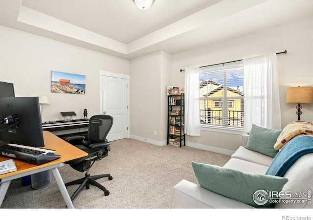 office area with light carpet and a raised ceiling