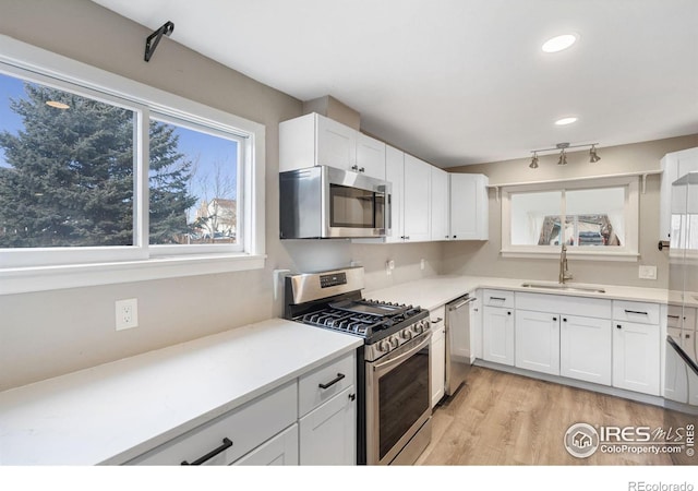 kitchen featuring sink, white cabinets, light wood-type flooring, and appliances with stainless steel finishes