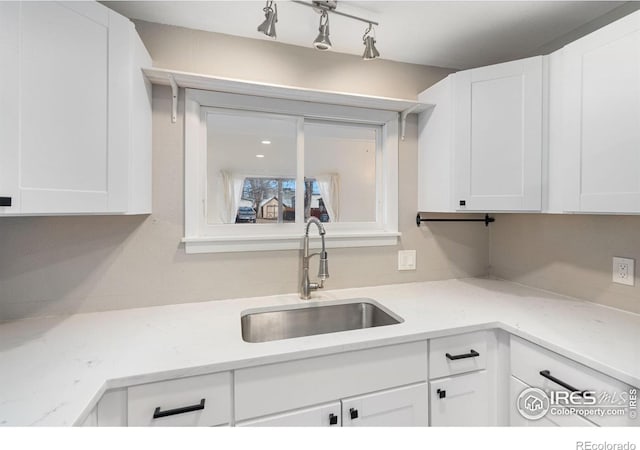 kitchen with sink, white cabinetry, and light stone counters