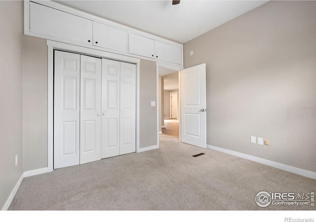 unfurnished bedroom with light colored carpet and a closet