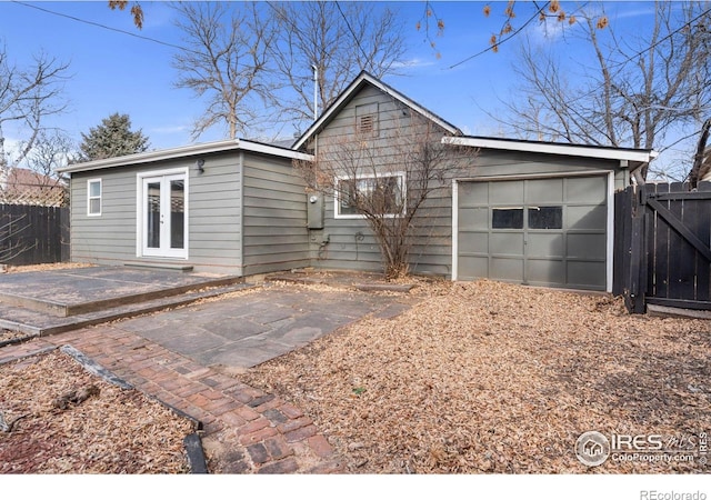 rear view of house featuring a garage and french doors