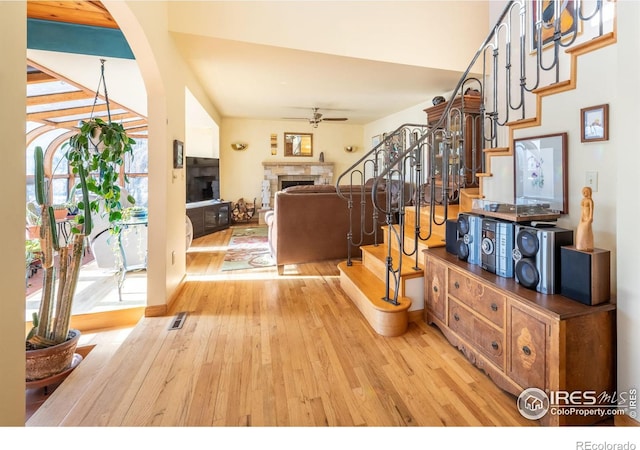 interior space with hardwood / wood-style flooring, ceiling fan, and a stone fireplace