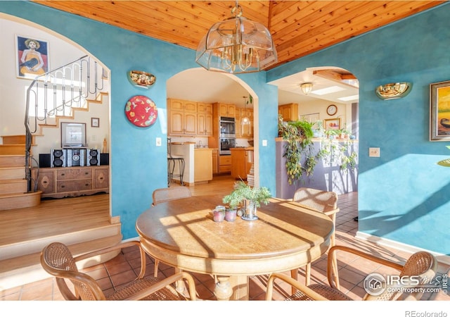 dining space featuring high vaulted ceiling, an inviting chandelier, wooden ceiling, and light tile patterned flooring