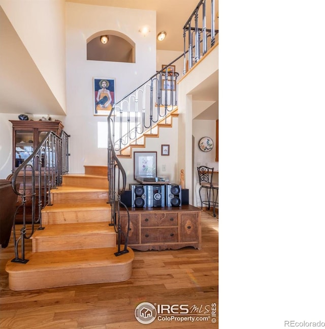 staircase with hardwood / wood-style flooring and a towering ceiling