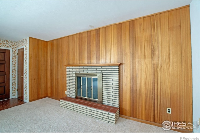 unfurnished living room featuring carpet floors, a fireplace, and wood walls