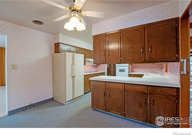 kitchen with sink, white appliances, ceiling fan, light colored carpet, and kitchen peninsula