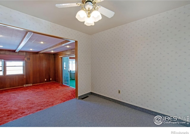 carpeted spare room with wooden walls