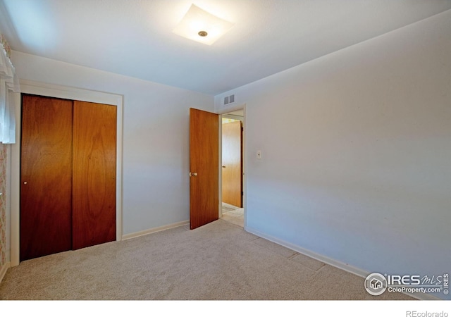 unfurnished bedroom with light colored carpet and a closet