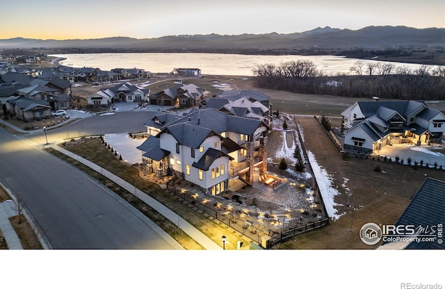 aerial view at dusk featuring a water and mountain view